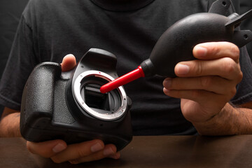 man cleaning his camera sensor using a blower, camera dslr cleaning concept