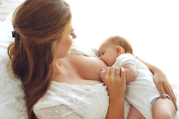 Young woman breastfeeding her baby at home. High quality photo.