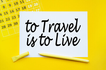 ABSTRACT CALENDAR, paper, pen on yellow background with text TO TRAVEL IS TO LIVE