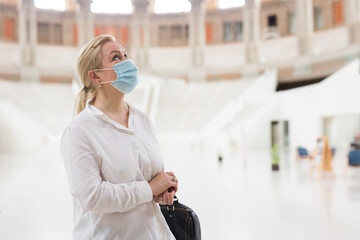 Portrait of attentive senior woman in protective face mask visiting museum