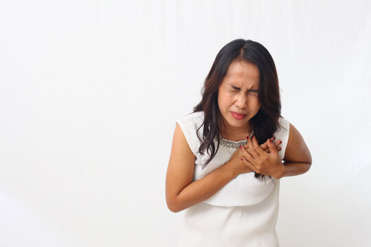Close up photo of asian woman over isolated white background having a pain in the heart or chest pain or heart attack