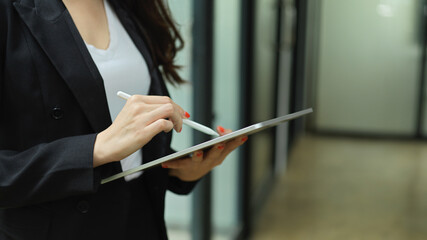 Side view of businesswoman working with digital tablet while standing in office