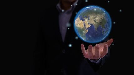 Businessman hand turn up in dark background with earth sphere floating  on top of palm and some flair around the globe planet. World of business and connectivity concept.