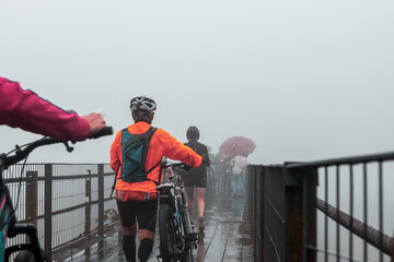 Pessoas caminhando na ponte de Paranapiacaba. Dia nublado, frio com névoa e neblina e chuva.