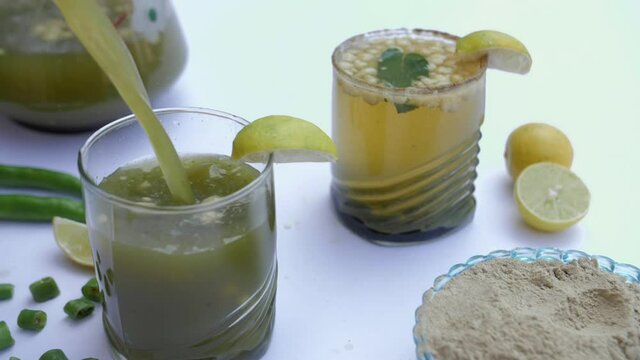 Cool summer beverage Jaljeera / Jal-jeera being poured in a transparent glass. An Indian drink prepared with cumin powder in water and served cold with mint leaves  lemon  green chilies  and Masala