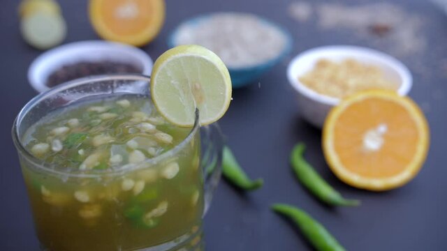 Lemon slices splashing in a fresh JalJira glass with Boondi and green chilies. Popular Indian spices whole black pepper  rock salt  green chilies  and orange slices - Summer drink India