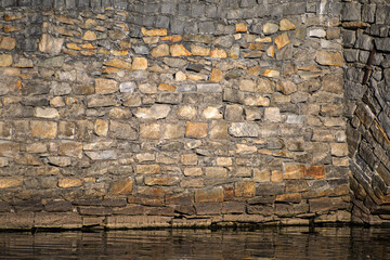 Stone wall near the river bank close-up