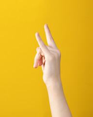 Naklejka premium teen hand with two fingers up shows goat gesture on yellow background. symbol of heavy metal and rock music