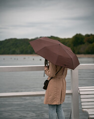 Romantic girl with umbrella on the wooden pier at the sea