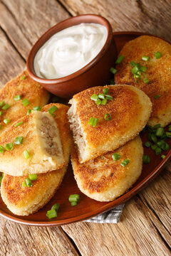 Potato zrazy with meat served with sour cream close-up in a plate on the table. Vertical