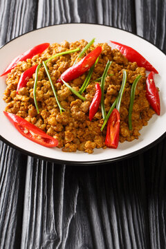 Khua kling is a spicy, dry fried curry from Thai cuisine closeup in the plate on the table. Vertical