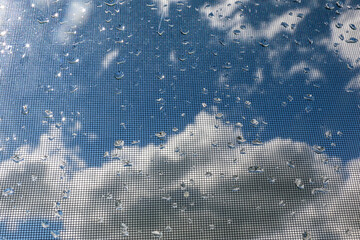 Tropfen vor Gitterstruktur mit Wolken im Hintergrund