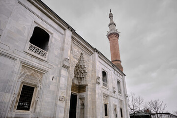 Obraz premium Bursa Turkey. Entrance gate of green mosque (Yesil camii) with magnificent carving and engraving works above the gate made of marble materials during rainy day with minaret made of bricks