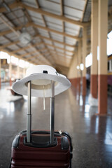Plastic suitcase and white hat on the railroad platform.  Holiday and travel concept.