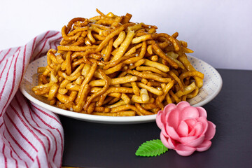 Chak chak stands on the table in a plate next to a red and white napkin. National dish of Tatars and Bashkirs