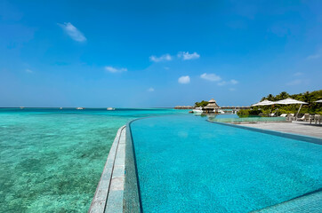 Fototapeta na wymiar Scenic landscape of Maldives beach and pier with speed boats and yachts on the horizon. Seascape with water bungalows, beautiful turquoise sea and lagoon waters, tropical nature paradise. 