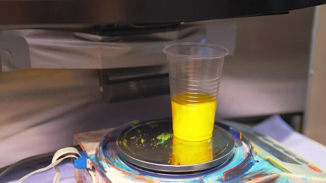Yellow paint is poured into the plastic cup. Tinting equipment