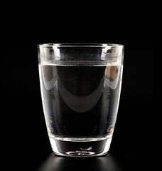 A glass of clear water on a black background