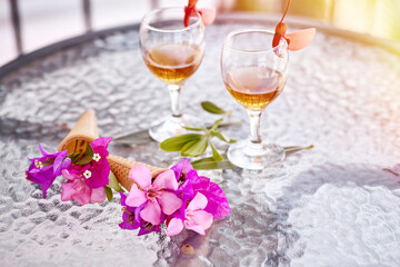 Summer cocktails with pink flowers of bougainvillea on glass table. Refreshment concept. Summer bright surreal flowers and homemade drinks. Copy space. High quality photo 