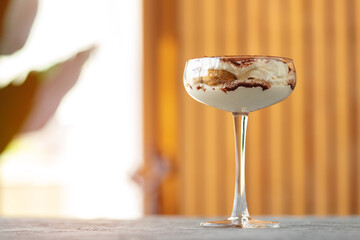Tiramisu dessert in a glass on gray surface