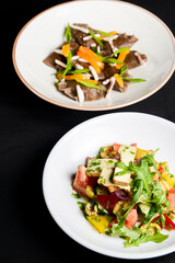 Buckwheat dumplings with fresh mushrooms and vegetable salad with cheese, fresh romatoes and cucumbers over black