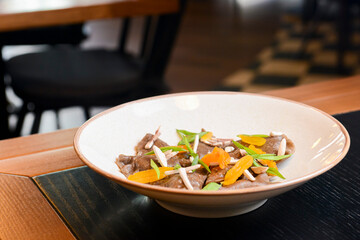 Buckwheat dumplings with fresh mushrooms served on a white plate on black table in restaurant.