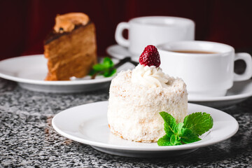 Coconut cake on a white plate with other food on the background.