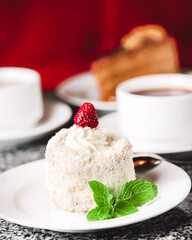 Coconut cake on a white plate with other food on the background.