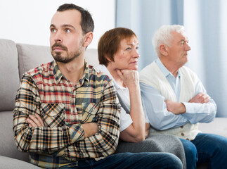 Aged grandparents and grandson are serious conversation at home and solve problems