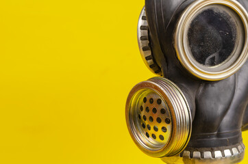 An old black military gas mask on a yellow background. Obsolete