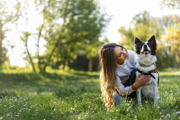 Beautiful woman with playful dog on fresh green meadow