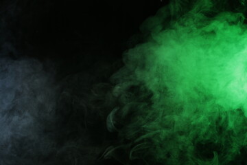 Artificial smoke in grey-green light on black background