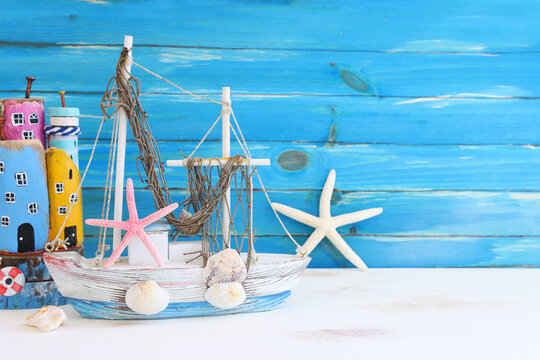 Top view of Nautical concept with sea life style objects as boat, driftwood beach houses, seashells and starfish over wooden background