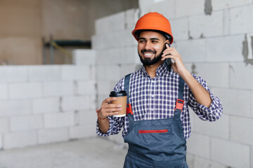 Professional bricklayer talking by smartphone on the construction site