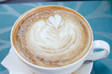 Coffee with foam in a cup is on the table. Coffee house