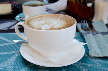 Coffee with foam in a cup is on the table. Coffee house