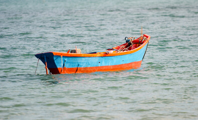 Small red boat in the water close to the beach

