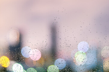 Rain drop on glass window in monsoon season with colorful bokeh light from city buildings...