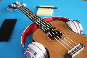 Fototapeta premium Headphones are putting on acoustic guitar on blue background closeup