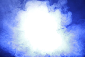 Fototapeta na wymiar Artificial smoke in blue light on black background