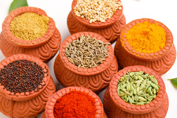 Indian spices collection, dried colorful condiment, nuts, pods and seeds and another spices in clay bowls.