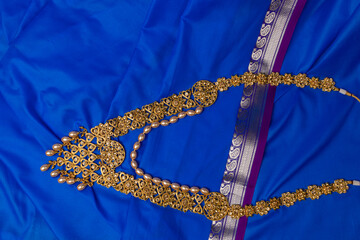Indian traditional gold Indian wedding women's jewelry on blue saree background. Close-up. Still-life.