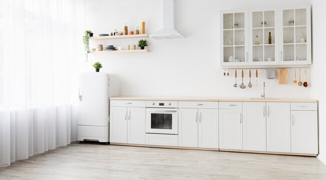 Minimal cozy scandinavian interior after repair. White kitchen furniture, refrigerator in simple dining room, panorama