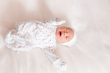 Little newborn baby lies on white sheet, view from above