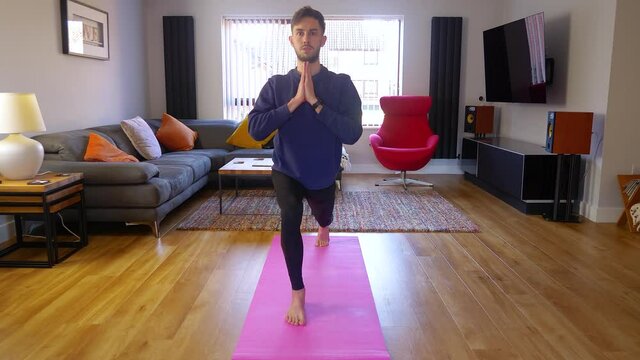 Home yoga, young male performing lunge yoga pose asana, indoors with cat