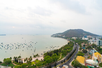 Panoramic coastal Vung Tau view from above, with waves, coastline, streets, coconut trees and Tao Phung mountain in Vietnam. Long exposure photography at sunset.