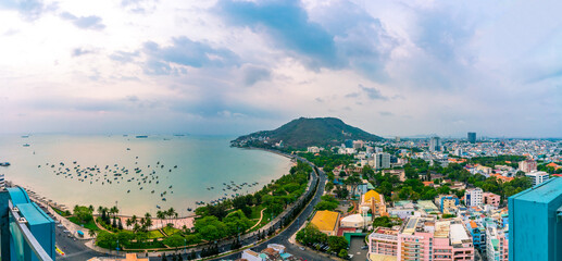 Panoramic coastal Vung Tau view from above, with waves, coastline, streets, coconut trees and Tao Phung mountain in Vietnam. Long exposure photography at sunset.