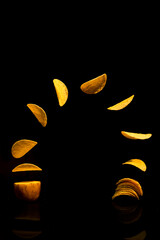 Close up of potato slice into potato chips isolated concept on black background with reflect shadow at bottom