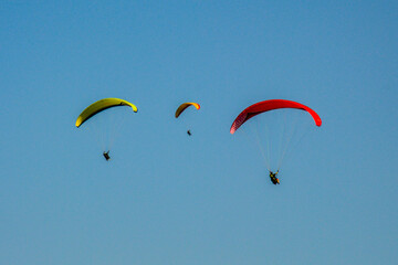 Three paragliders flying high in the blue sky