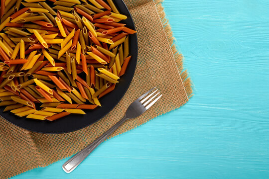 Raw pasta on a black plate, top view, copy space